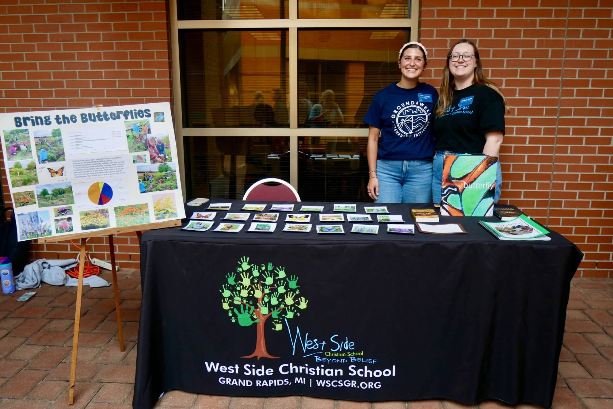 Two educators standing in front of their table at the Groundswell Student Project Showcase